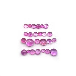 Peut inclure: Une collection de vingt-deux pierres précieuses roses, rondes et libres, disposées en quatre rangées horizontales. Les pierres varient en taille et présentent une surface lisse, polie et de style cabochon, aux tons rose vif translucides.