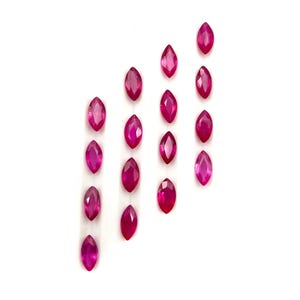 May include: A collection of thirteen loose, marquise-cut gemstones in a vibrant, deep pinkish-red hue. Each stone features a faceted surface that reflects light, arranged in four vertical columns of varying lengths against a plain white background.