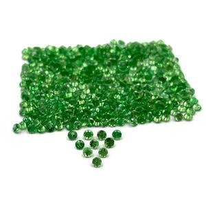 May include: A large collection of small, round, faceted green gemstones arranged in a rectangular cluster, with ten additional individual green gemstones positioned in a triangular formation directly below the main group.