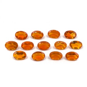 Könnte beinhalten: Eine Sammlung von zwölf ovalen orangefarbenen Edelsteinen. Die Edelsteine sind glatt und poliert und haben einen warmen, bernsteinfarbenen Farbton.