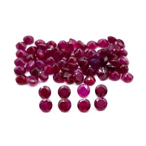 Könnte beinhalten: Eine große Gruppe runder, roter Rubin-Edelsteine, mit einer kleineren Gruppe von 8 Edelsteinen im Vordergrund.