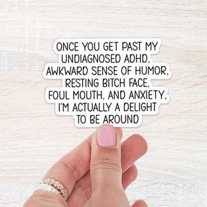 Peut inclure: Un autocollant blanc découpé avec le texte noir suivant : ONCE YOU GET PAST MY UNDIAGNOSED ADHD, AWKWARD SENSE OF HUMOR, RESTING BITCH FACE, FOUL MOUTH, AND ANXIETY, I'M ACTUALLY A DELIGHT TO BE AROUND. L'autocollant a une finition mate et lisse.