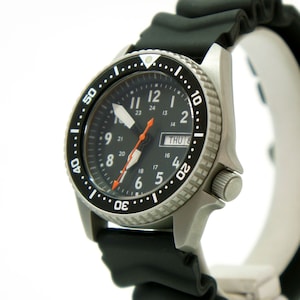 May include: A black and silver wristwatch with a black rubber band. The watch face has a black background with white numbers and hands, and a small date window that reads "THU 14".