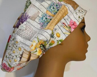 May include: A white and gray patterned scrub cap featuring a floral design with daisies, lavender, and other flowers. The cap has a basket and wooden plank design. The text "Fresh Lavender" is visible on the cap.