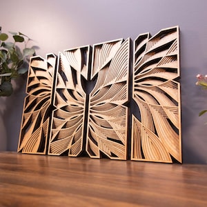 May include: Three wooden wall panels with a geometric design. The panels are made of light brown wood and have a layered, 3D effect. The design is reminiscent of a stylized butterfly.