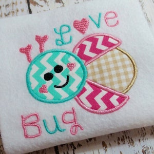 Op de afbeelding: Een witte stoffen applicatie met een roze en turquoise geborduurd ontwerp van een kever. De kever heeft een chevron-patroon en een glimlachend gezicht met roze hartjes. De tekst "I love bug" is in roze geborduurd.