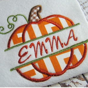 May include: Embroidered pumpkin design with the name "EMMA" in orange thread. The pumpkin features orange and white striped segments, a brown and white checkered stem, and green vines. The design is on a white background.
