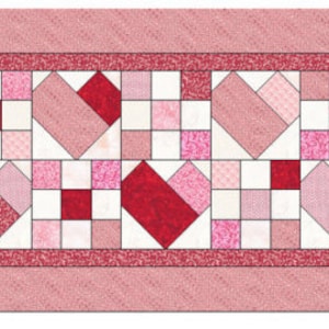 Può includere: Una tovaglia trapuntata con un motivo ripetuto di cuori e quadrati nelle tonalità del rosso e del rosa. Il design include una varietà di trame e motivi, con un bordo rosa a tinta unita. La tovaglia è larga circa 30 cm.