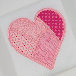 May include: A pink patchwork heart with a pink satin stitch outline. The heart is made of different pink fabrics with various patterns, including polka dots, floral, and geometric designs.