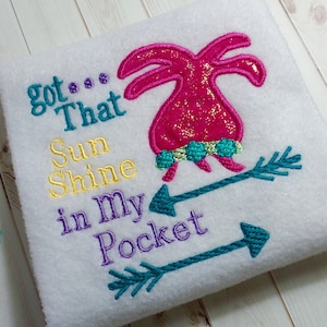 May include: Embroidered design on a white fabric with the text "got... That Sunshine in my Pocket" and a pink glittery palm tree with turquoise arrows.