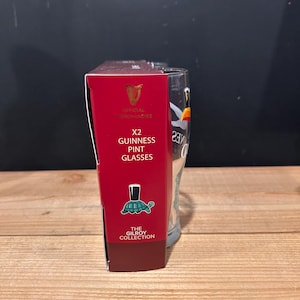 May include: A red box with the text "X2 Guinness Pint Glasses" next to a clear pint glass. The box has the Guinness logo and the words "Official Merchandise". The box also has a turtle illustration.