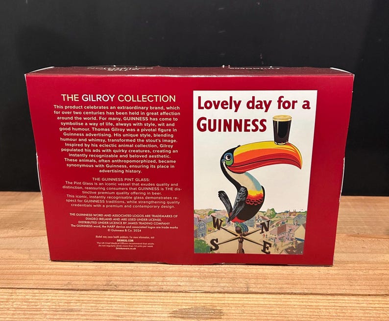 May include: A red box featuring a Guinness advertisement. The advertisement shows a toucan with a pint of Guinness on its beak, with the text "Lovely day for a Guinness". The box also has text about the Gilroy Collection.