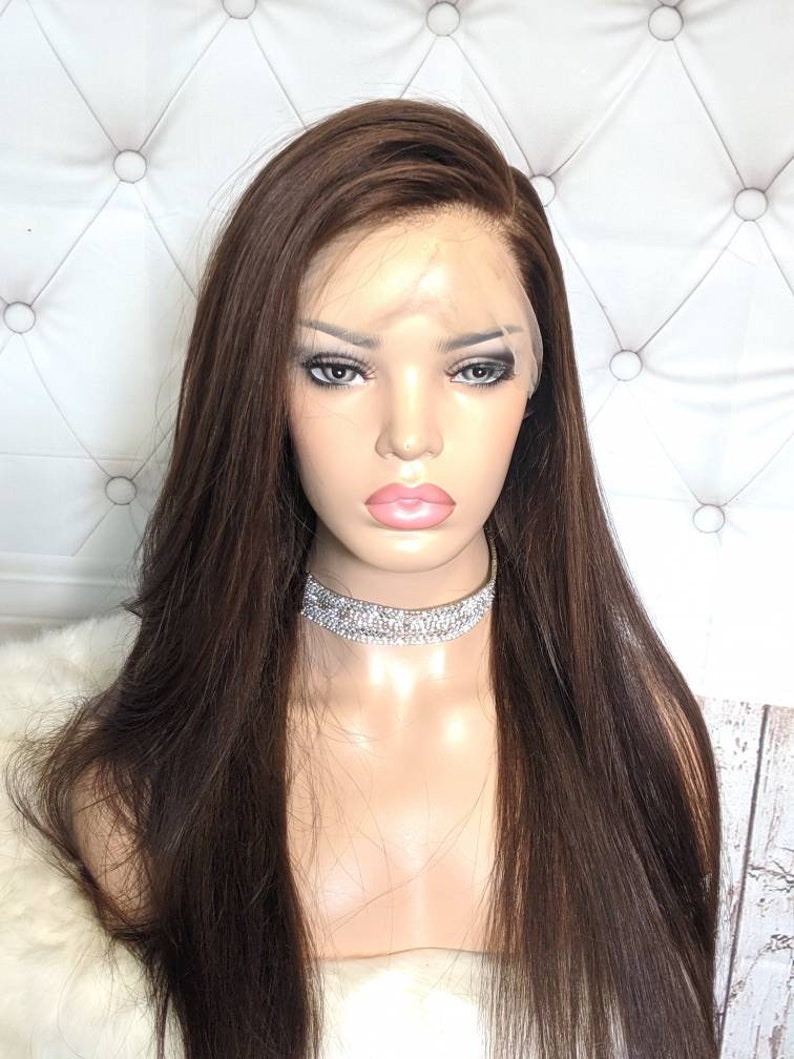 May include: A long, straight, dark brown human hair wig with a lace front. The wig is styled with a side part and falls to the shoulders.