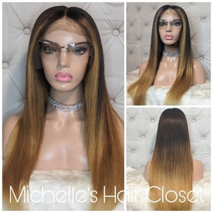 Może przedstawiać: Długa, prosta peruka ombre z włosów ludzkich z ciemnymi korzeniami, które stopniowo rozjaśniają się do jasnego blondu na końcach. Peruka jest ułożona z przedziałkiem na środku i jest noszona na głowie manekina. Manekin nosi okulary.