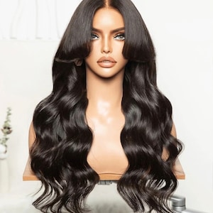 Może przedstawiać: Długa, czarna, falująca peruka z włosów ludzkich z koronką z przodu. Peruka jest ułożona z przedziałkiem z boku i długimi, luźnymi falami.