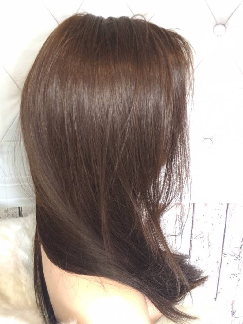 May include: A long, straight, brown wig with a natural-looking parting. The wig is styled in a simple, sleek way, with the hair falling straight down the back.
