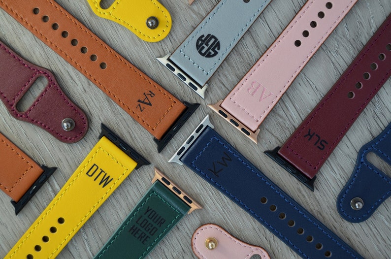 May include: Assortment of leather watch bands in various colors, including yellow, brown, pink, red, blue, and green. Each band features a personalized monogram or text, such as "DTW", "RAZ", "KW", "SLK", "AB", and "YOUR LOGO HERE".