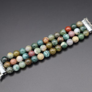 Puede incluir: Un brazalete de cuentas de &aacute;gata multicolor con cierre de metal plateado, dise&ntilde;ado para un Apple Watch.