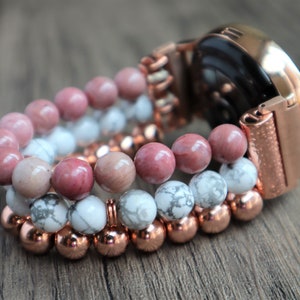 May include: A rose gold smartwatch with a beaded band. The band is made of three strands of beads: pink, white, and copper.