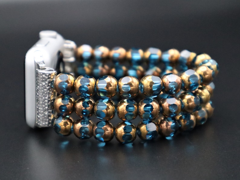 May include: A watch band made of blue and gold beads. The band is made of multiple strands of beads, and it is designed to fit a smartwatch.