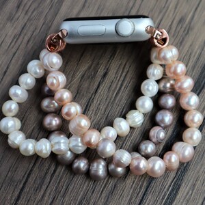 Puede incluir: Un brazalete de perlas con un accesorio de banda de reloj de oro rosa. El brazalete est&aacute; hecho de tres hebras de perlas en blanco, crema y rosa claro.