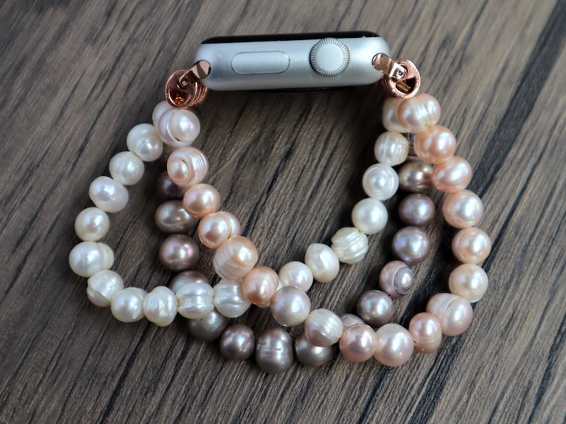 Puede incluir: Un brazalete de perlas con un accesorio de banda de reloj de oro rosa. El brazalete est&aacute; hecho de tres hebras de perlas en blanco, crema y rosa claro.