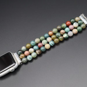 Puede incluir: Una pulsera de reloj de cuentas de &aacute;gata multicolor con cierre de plata. La pulsera est&aacute; hecha de cuentas redondas en tonos verdes, marrones y rosas.