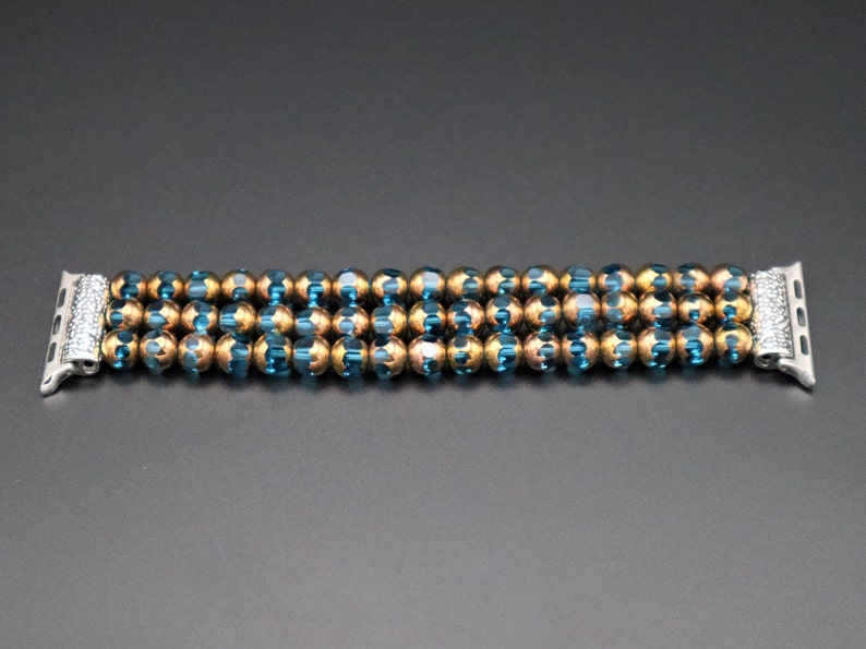 May include: A beaded watch band with alternating blue and gold beads. The band is designed to fit an Apple Watch.