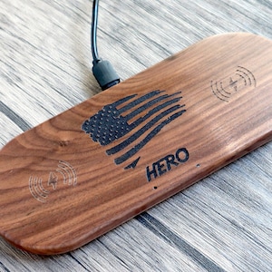 Peut inclure: Un chargeur sans fil en bois avec un motif de drapeau américain et le mot "HERO" gravé dessus. Le chargeur a deux bobines de charge, indiquées par les symboles d'éclairs.