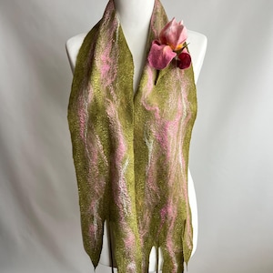 May include: A handmade felt scarf in olive green with pink and white swirls, adorned with a pink felt flower. The scarf has a unique, fringed bottom edge with pink accents, displayed on a mannequin.