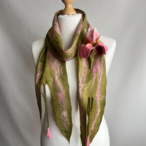 May include: A green and pink felt scarf with a floral accent. The scarf is draped on a mannequin, showcasing a design with vertical stripes of green and pink. A pink felt flower is attached to the scarf, adding a touch of elegance.
