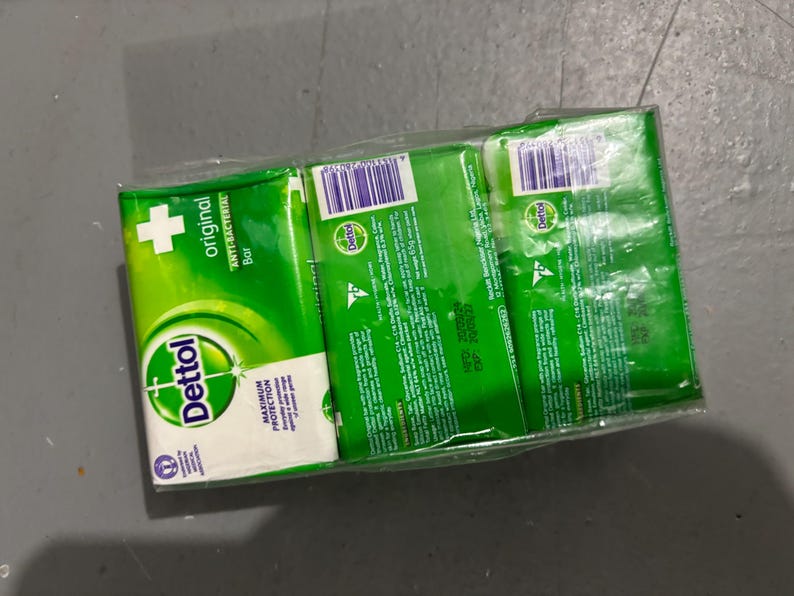 May include: A three-pack of Dettol Original Anti-Bacterial soap bars wrapped in clear plastic. Each green and white rectangular package features the Dettol logo, the text Original Anti-Bacterial Bar, and a net weight of 65g printed on the back.