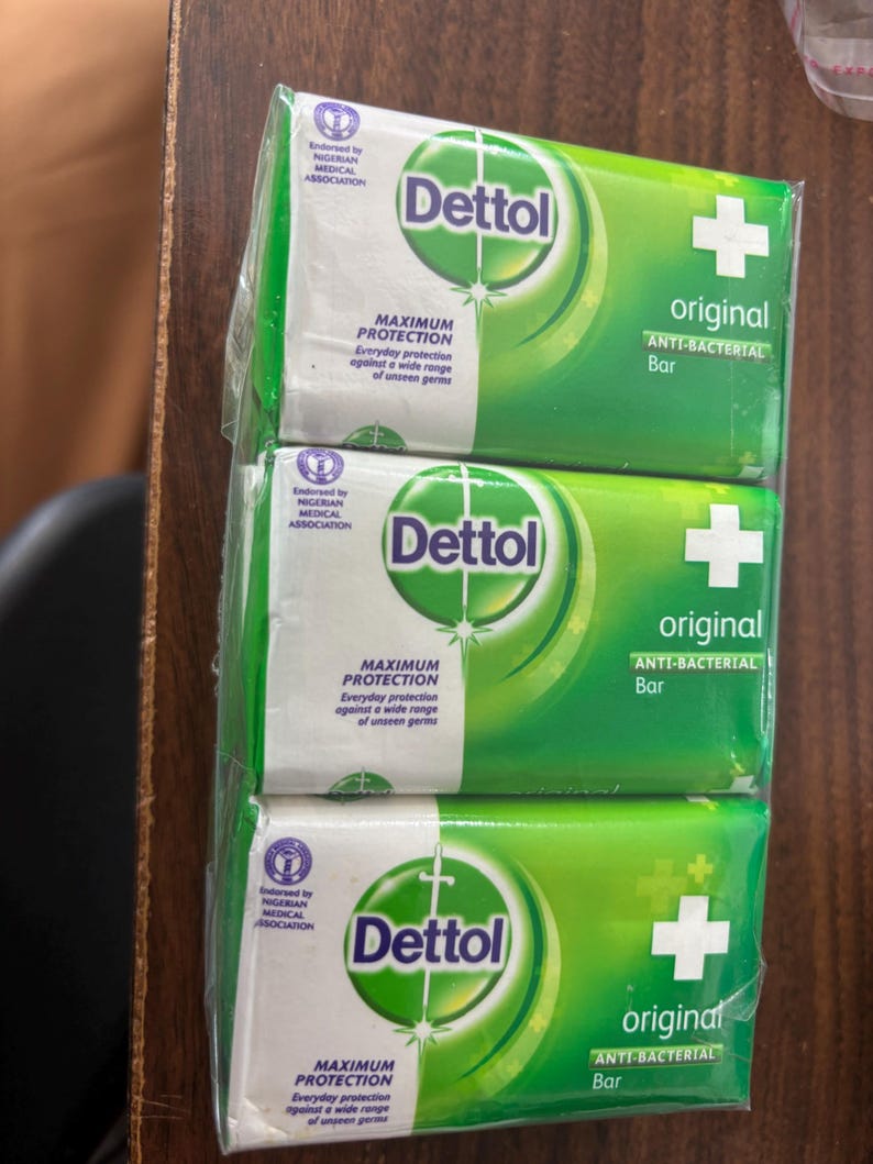 May include: A three-pack of Dettol Original anti-bacterial soap bars wrapped in clear plastic. Each green and white rectangular package features the Dettol logo, a white cross, and the text Maximum Protection, Everyday protection against a wide range of unseen germs.