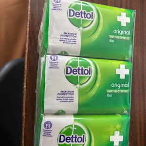 May include: A three-pack of Dettol Original anti-bacterial soap bars wrapped in clear plastic. Each green and white package features the Dettol logo, a white cross, and the text Maximum Protection, Everyday protection against a wide range of unseen germs.