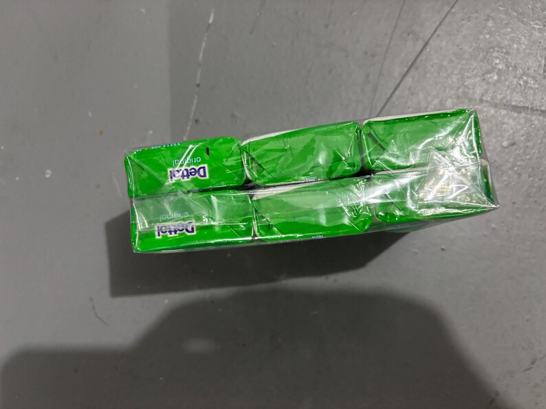 May include: A multi-pack of Dettol Original soap bars wrapped in clear plastic film. The packaging features a vibrant green color scheme with the white Dettol logo and the word original printed clearly on the front of each individual soap bar.