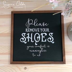May include: A black chalkboard sign with a wooden frame, reading "Please remove your shoes...your comfort is meaningless to us".