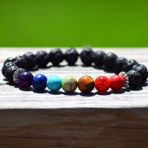 May include: A black lava rock bracelet with seven chakra beads. The beads are purple, blue, turquoise, green, brown, red, and orange.