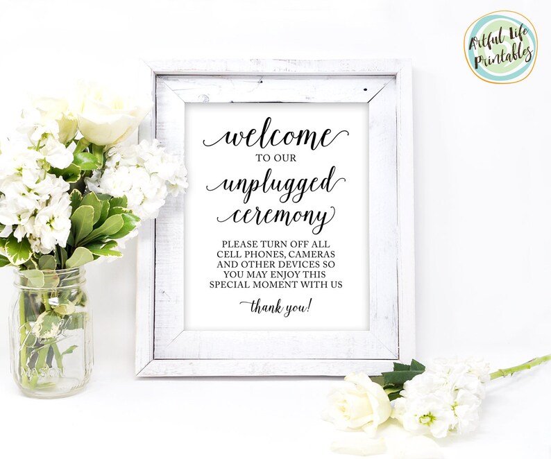 May include: A white framed sign with black text that reads "Welcome to our unplugged ceremony. Please turn off all cell phones, cameras and other devices so you may enjoy this special moment with us. Thank you!"