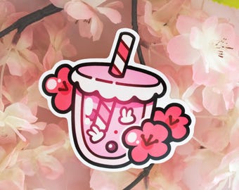 May include: A pink bubble tea sticker with a white rim and a striped straw. The drink features a bunny design and is decorated with pink flowers. The sticker is set against a background of pink flowers.
