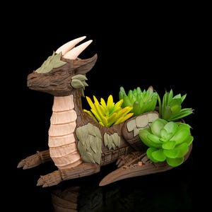 May include: A brown dragon-shaped planter with a light tan underbelly and cream-colored horns. The dragon's back is filled with vibrant green and yellow succulents. The planter is made of a textured material, giving it a rustic appearance.