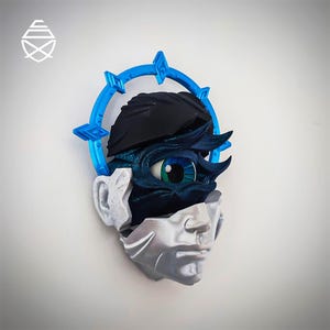 May include: A wall-mounted sculpture of a stylized human face, featuring a blue halo and a detailed eye. The sculpture is composed of multiple sections, with a mix of blue, black, and silver tones. The eye is a focal point.