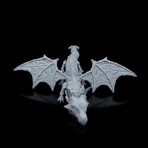 May include: A detailed, gray dragon figurine with outstretched wings. The dragon has a textured surface, sharp claws, and a detailed face. The wings are spread wide, showcasing intricate vein patterns. The figurine is set against a black background.