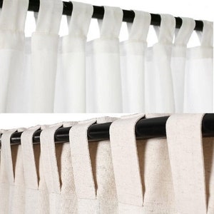 May include: Two sets of white sheer curtains with a black rod. The top set is gathered at the top with a simple fold. The bottom set is gathered at the top with a more elaborate fold.