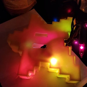 May include: A white plastic light-up sign shaped like the number 8. The sign is illuminated with red, yellow, and green lights.