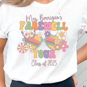 May include: White t-shirt with a retro-style graphic design featuring the text "Mrs. Berrigan's Farewell Tour Class of 2025" with colorful flowers and sunglasses.