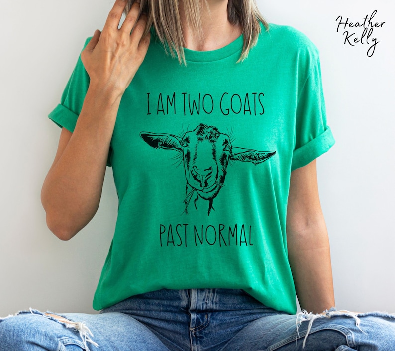 May include: A green t-shirt with a black and white illustration of a goat's face and the text "I am two goats past normal".