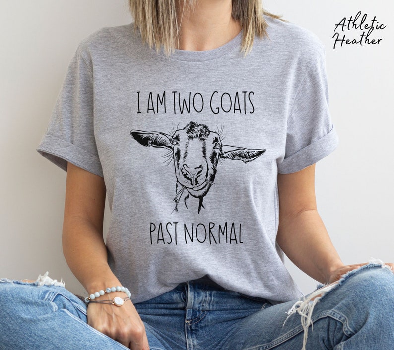 May include: A gray t-shirt with the text "I am two goats past normal" and a black and white illustration of a goat's head.