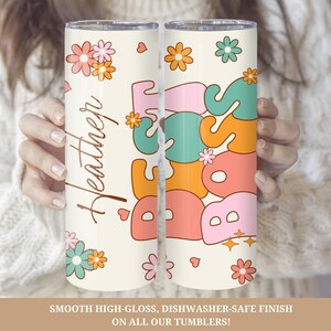 May include: A white stainless steel tumbler with a pink, orange, green, and blue "Boss" graphic and a floral design. The tumbler has a personalized name, "Heather", on the side.