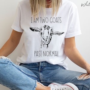 May include: White t-shirt with a black and white illustration of a goat's face and the text "I am two goats past normal".