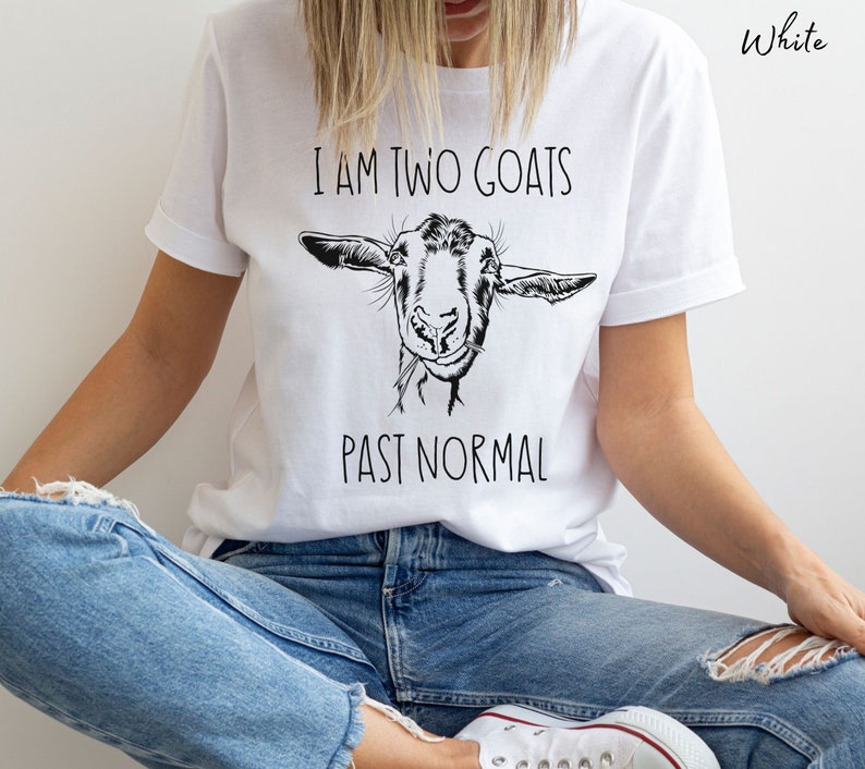 May include: White t-shirt with a black and white illustration of a goat's face and the text "I am two goats past normal".